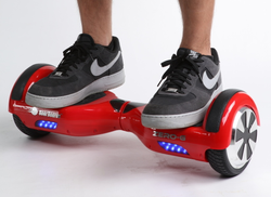 Red self-balancing two-wheeled board with a person standing on it.png